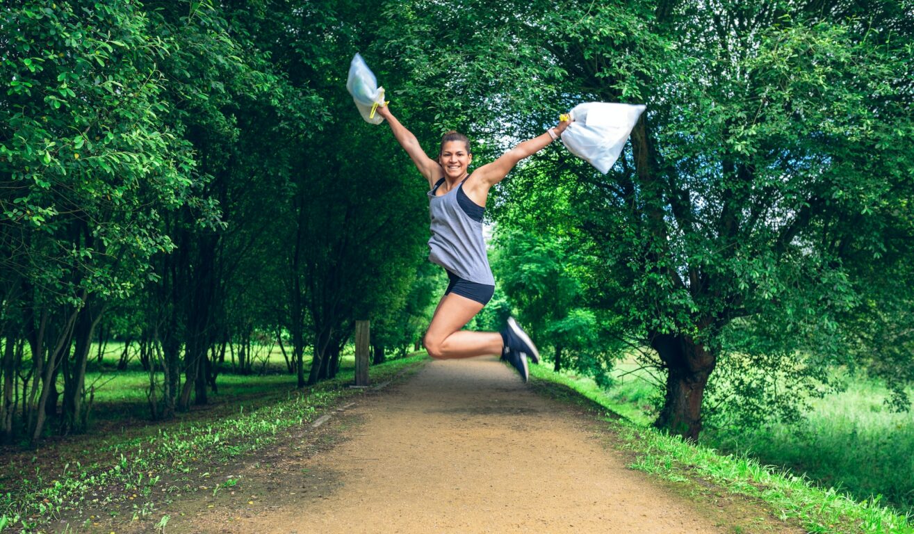 Girl jumping with trash bags after plogging