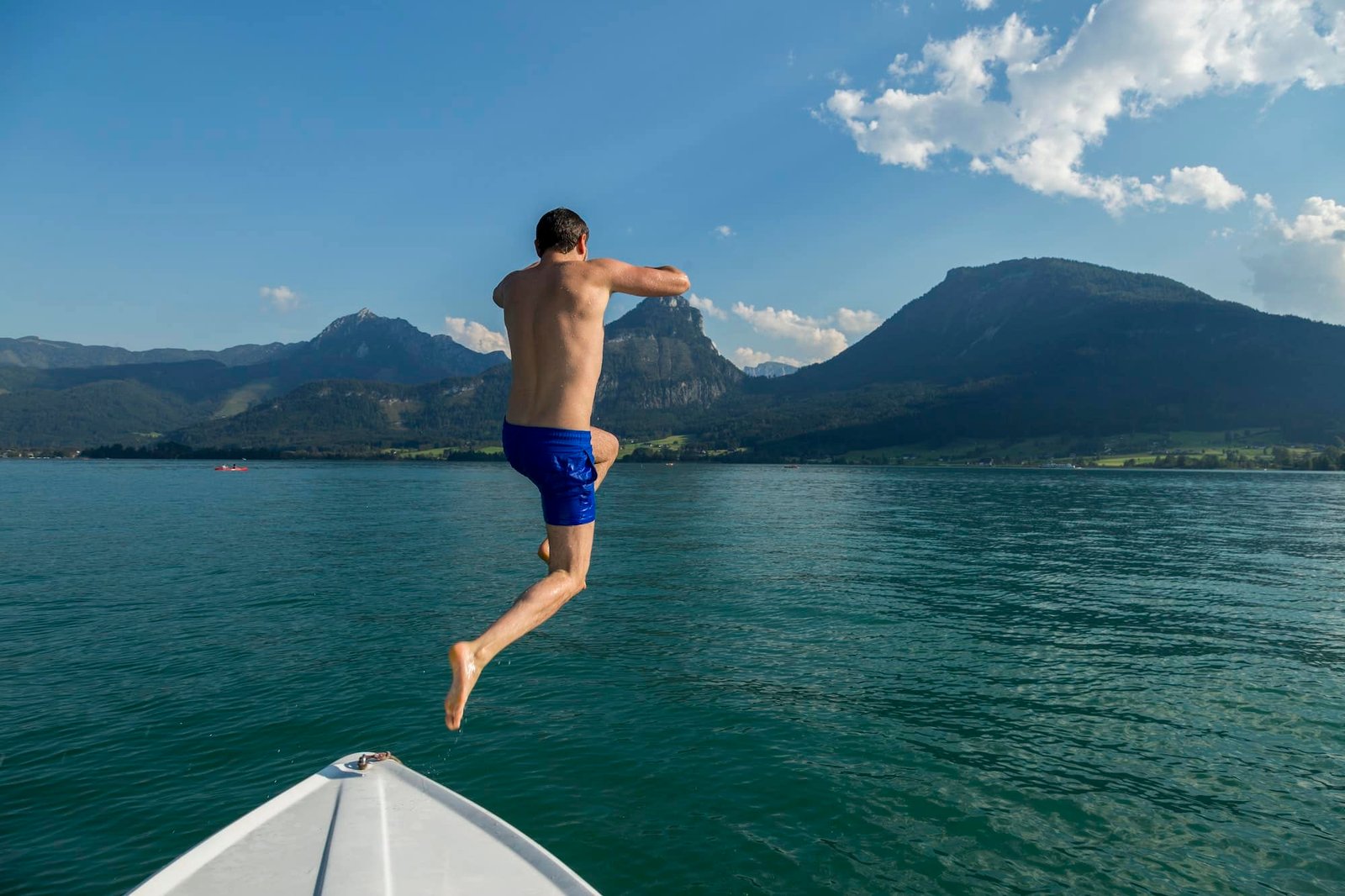 Austria, Sankt Wolfgang, man jumping from boat into lake