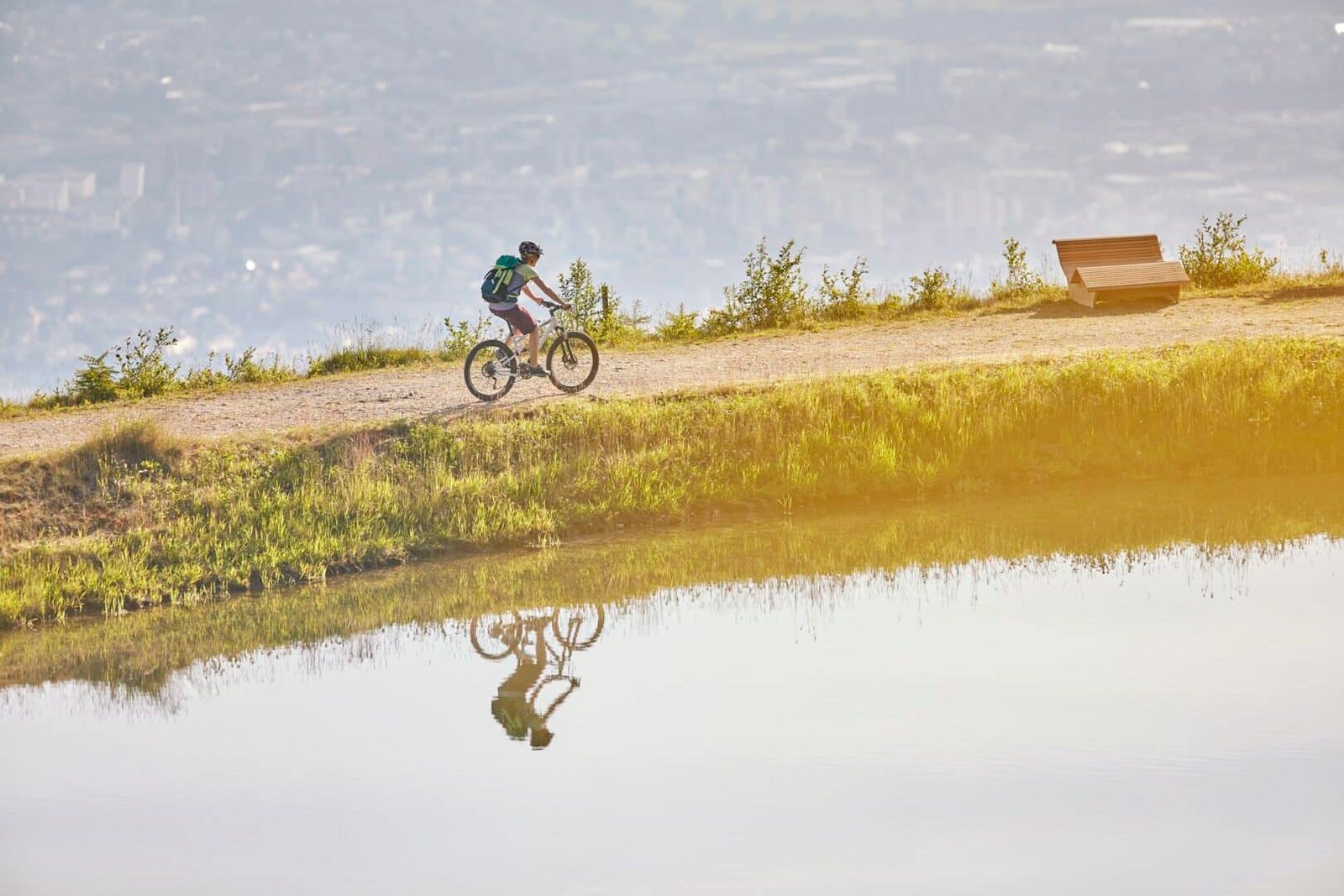 Austria, Tyrol, female mountainbiker at lake in the evening light