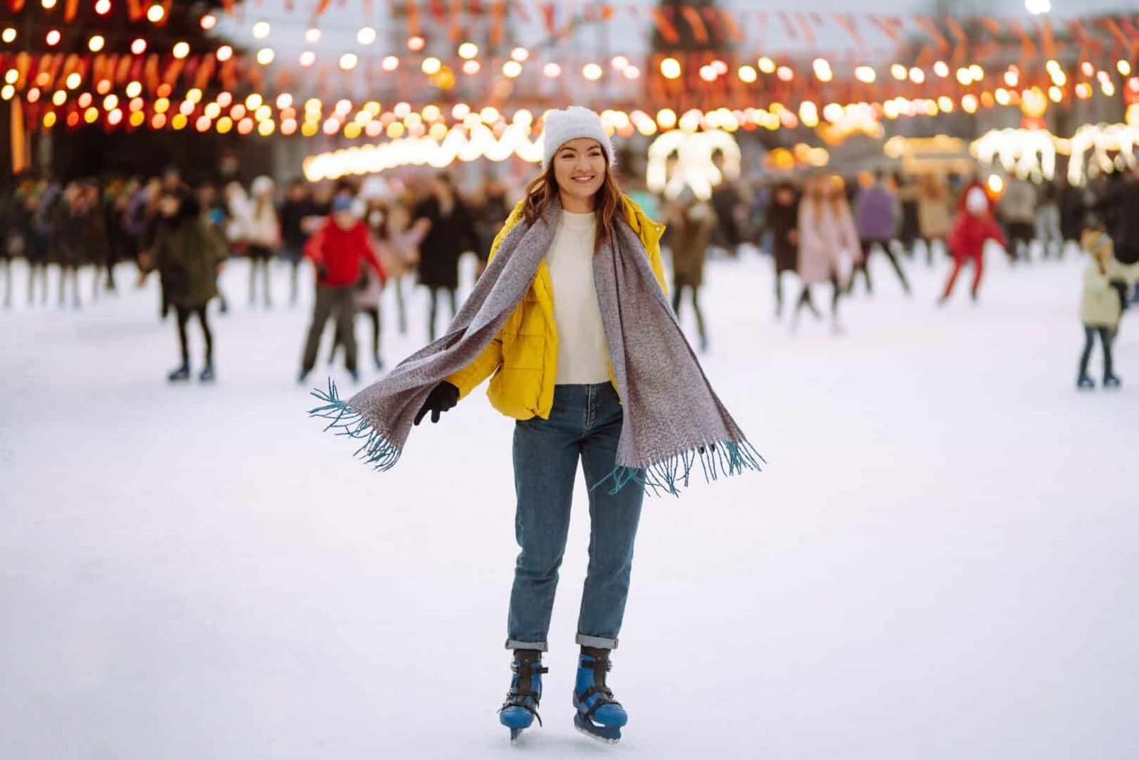 Happy woman ice skating on the ice arena in the city square on Festive Christmas fair. Cold weather.