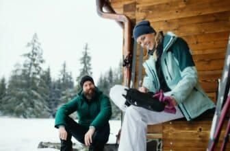 Mature couple resting by wooden hut outdoors in winter nature, cross country skiing.