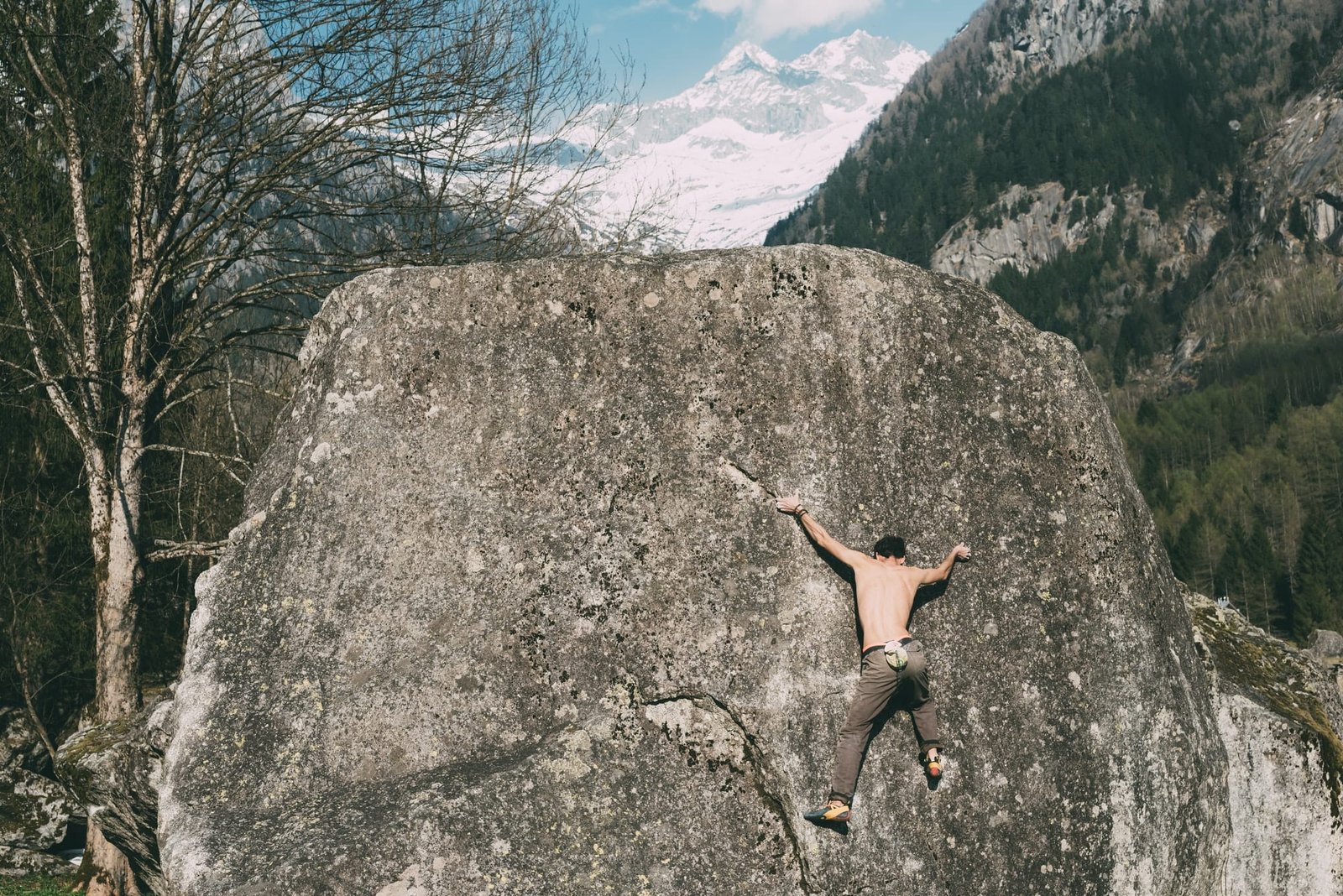 Rear view of young male boulderer climbing boulder, Lombardy, Italy