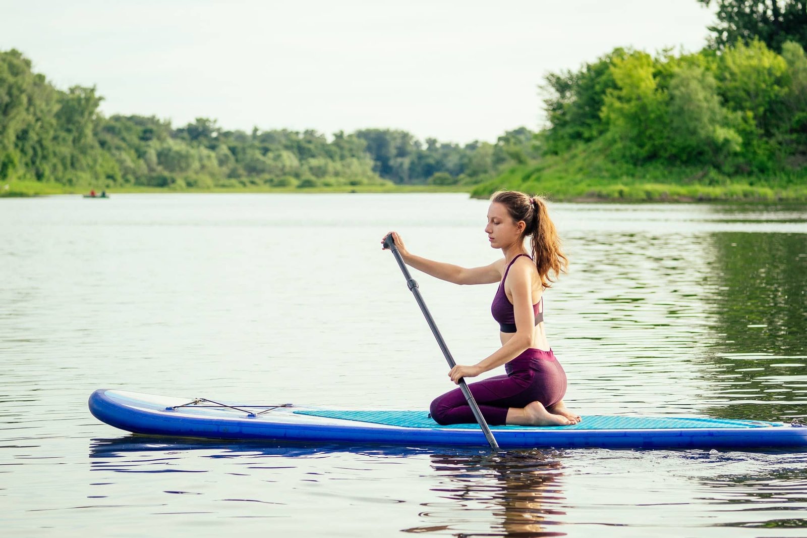 woman on sup sup board in nature at evening