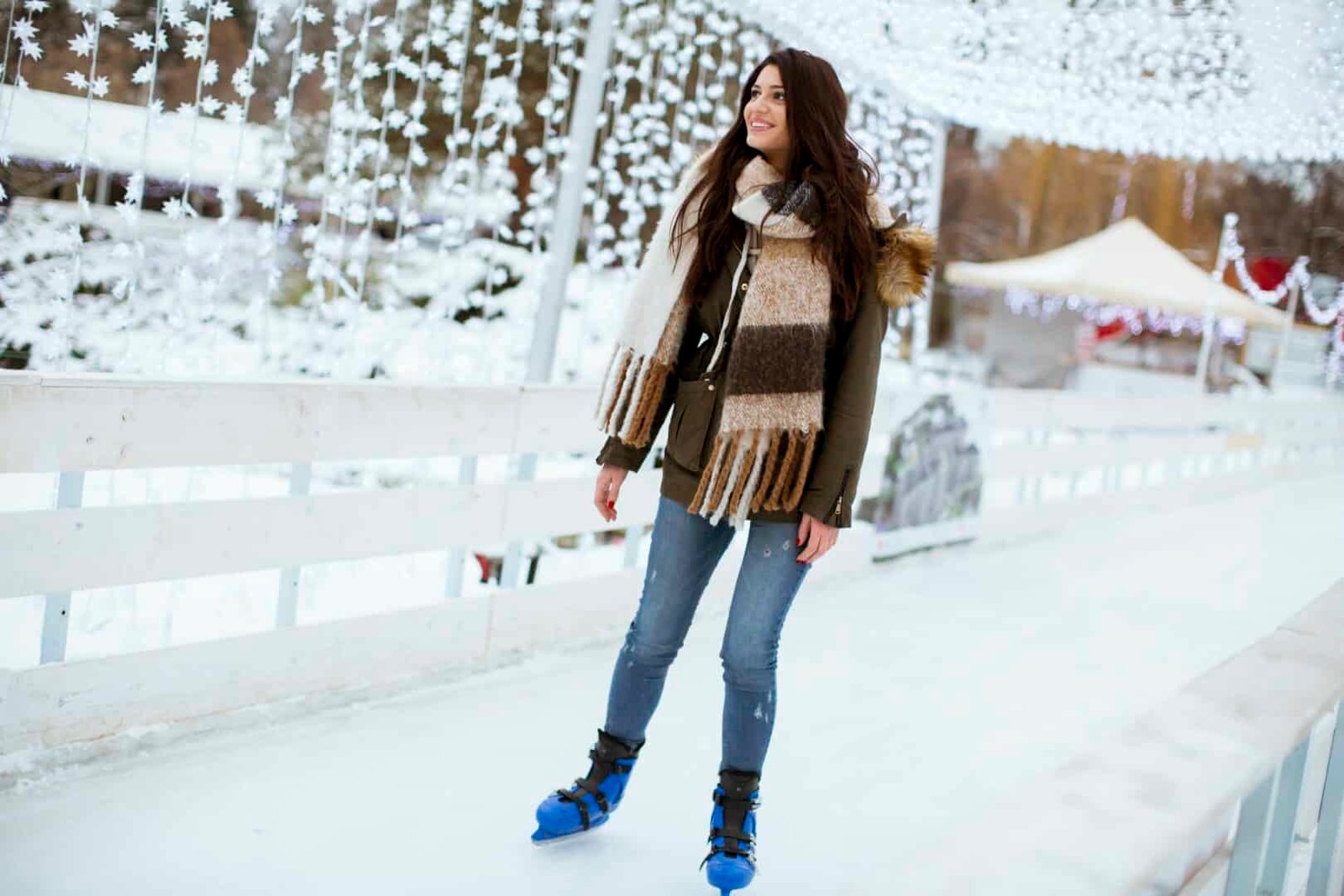 Young woman rides ice skates in the park on Christmas market