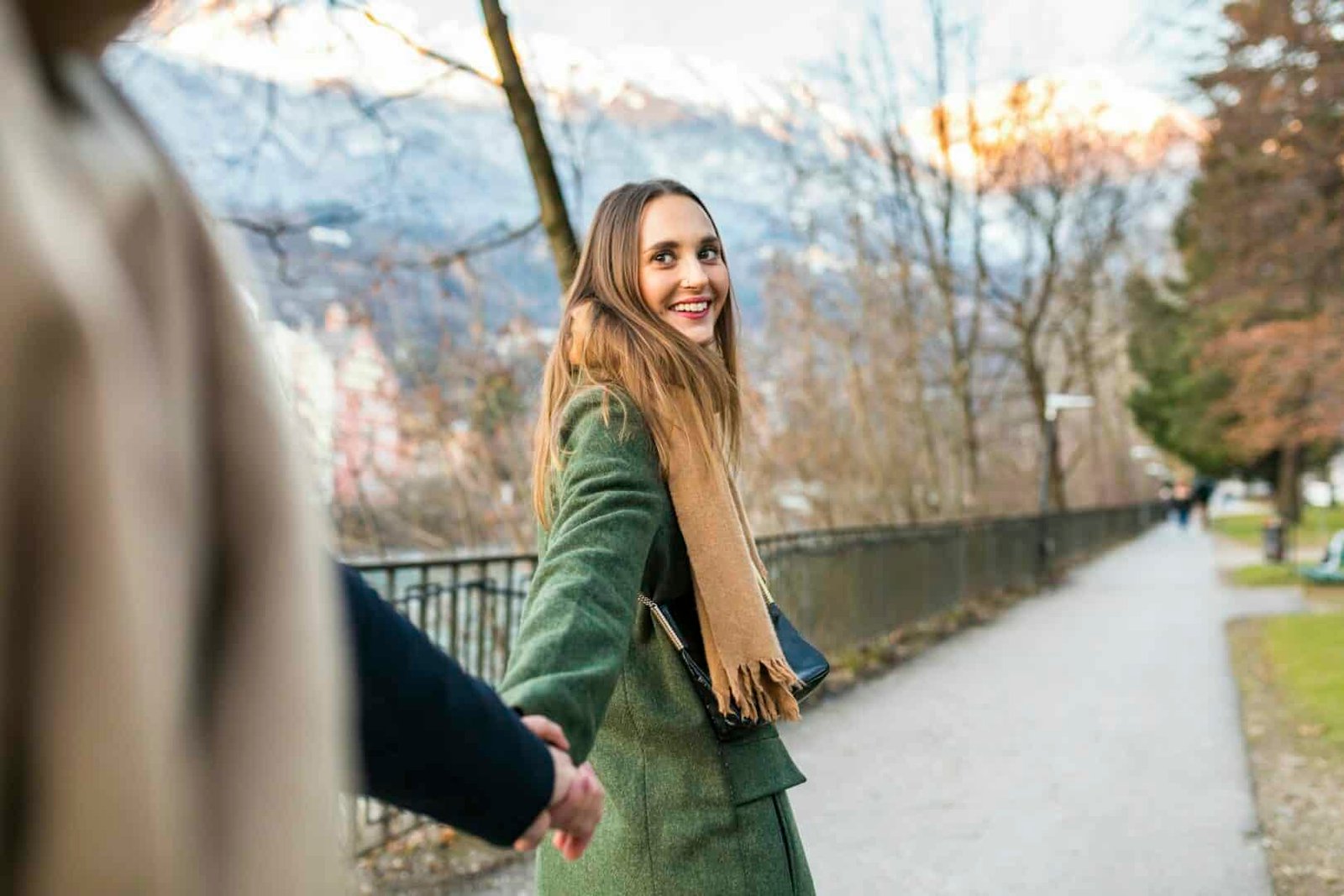 Austria, Innsbruck, portrait of happy young woman strolling hand in hand with her boyfriend at winte