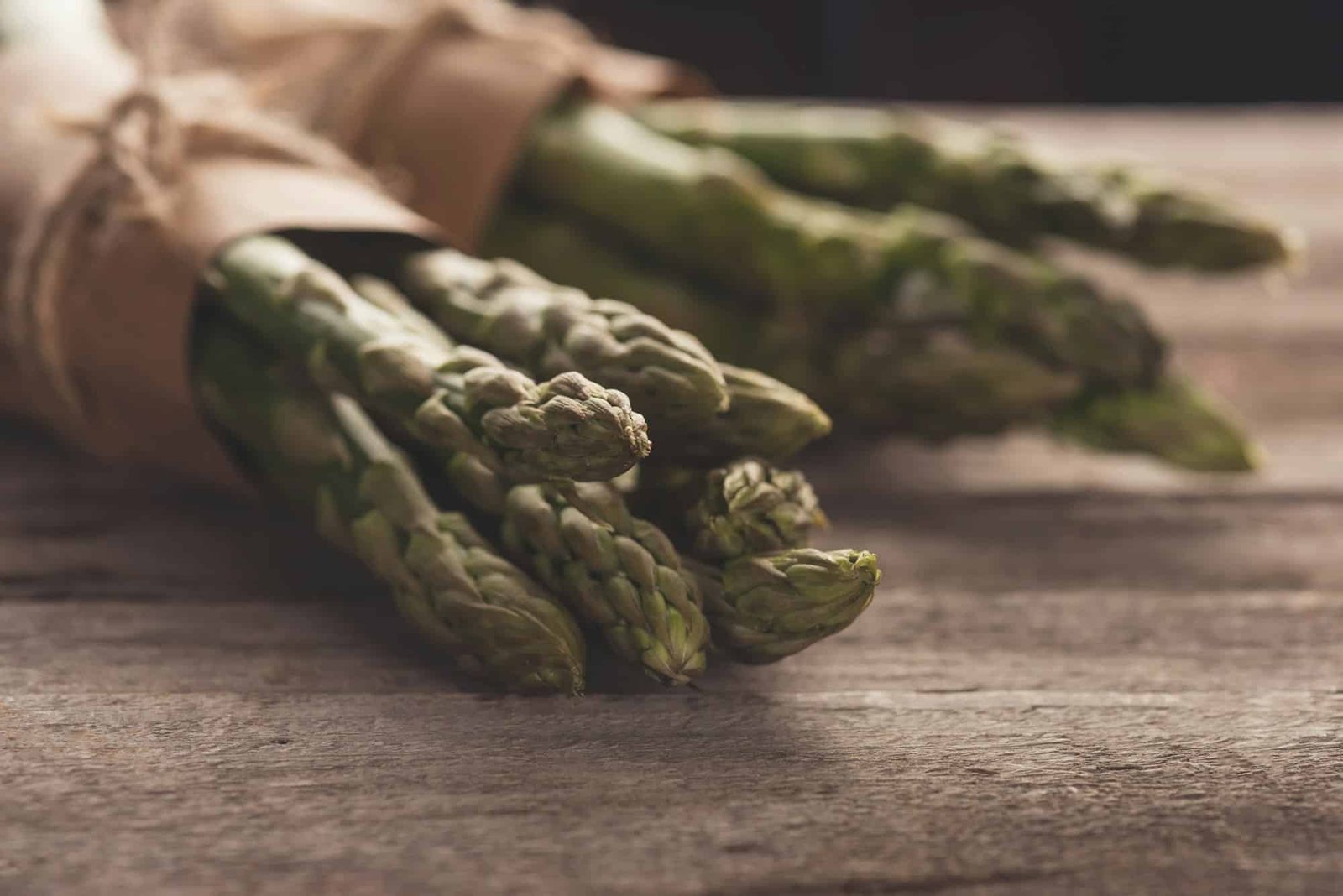 bunches of fresh green asparagus on wooden tabletop