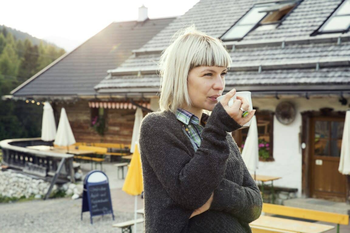 Woman drinking coffee outside hotel, Sattelbergalm, Tirol, Austria