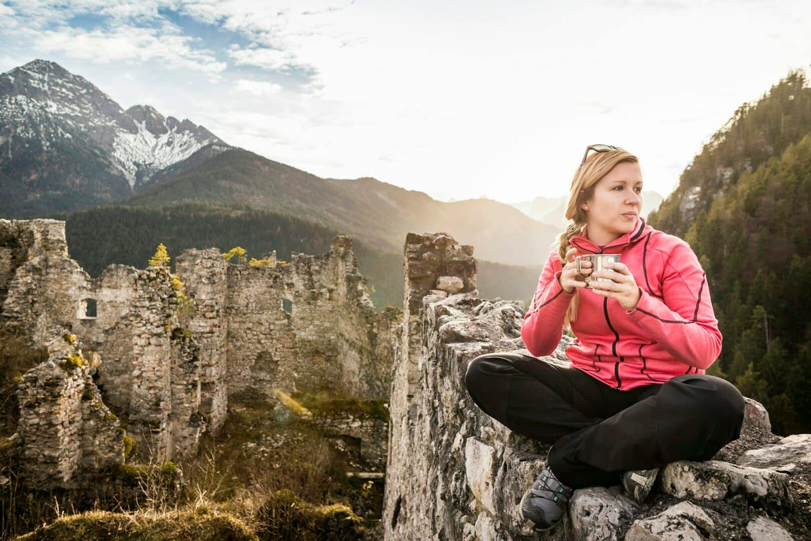 Young woman drinking coffee on top of Ehrenberg castle ruins, Reutte, Tyrol, Austria