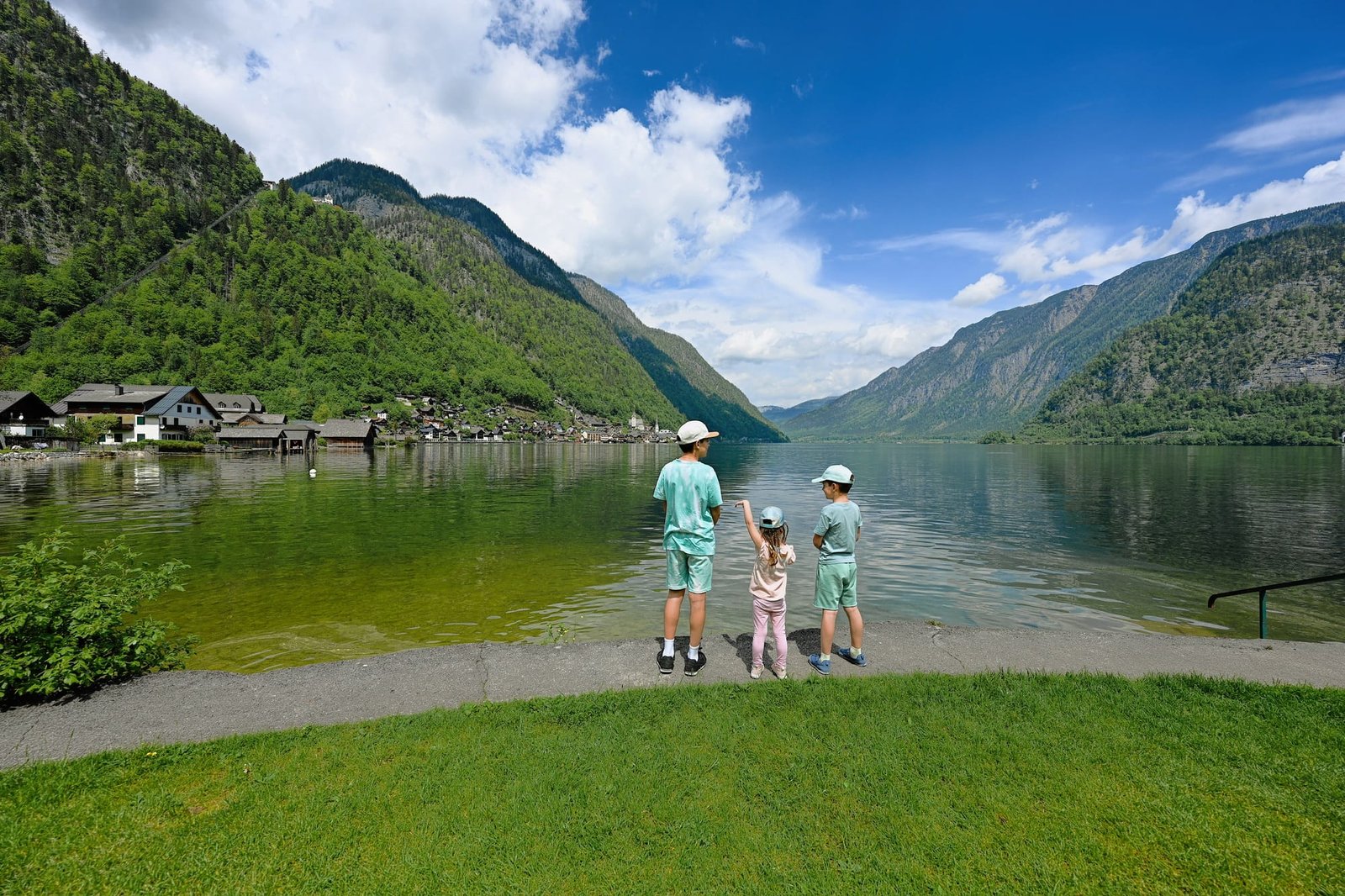Three kids over Austrian alps lake in Hallstatt, Salzkammergut, Austria.