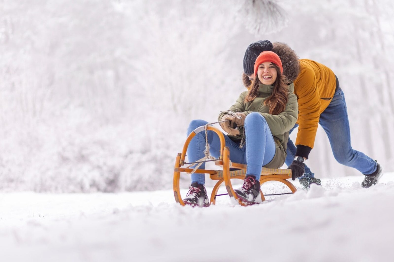 Boyfriend pushing girlfriend on sledge