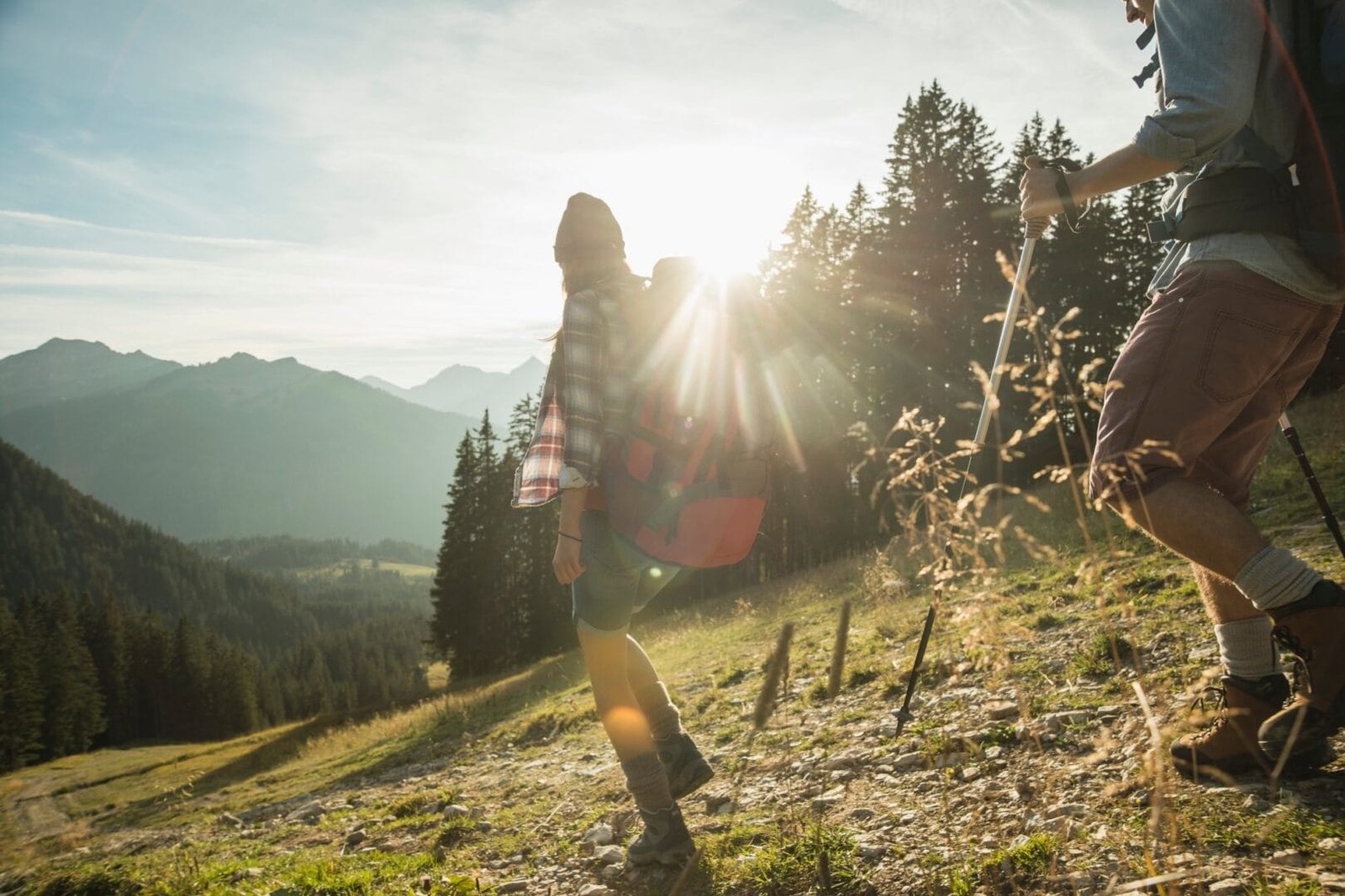 Austria, Tyrol, Tannheimer Tal, young couple hiking in sunlight on alpine meadow